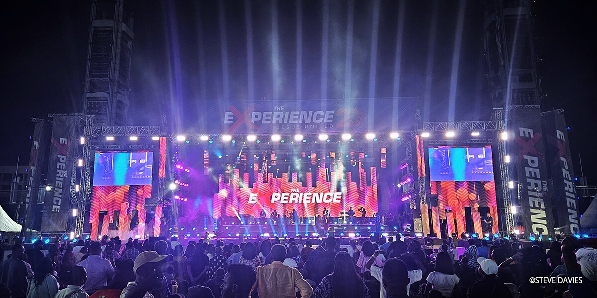 奈及利亞拉哥斯 The Experience 2025 的廣角視野，展示了配備燈光和影像螢幕的大型戶外舞台，在年度福音音樂活動期間於信徒人群前進行演出。
